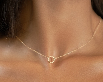 May include: A gold necklace with a simple circle pendant. The necklace is delicate and minimalist, making it a perfect everyday piece of jewelry.