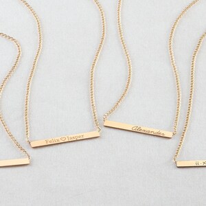 May include: Four gold necklaces with personalized bar pendants. The pendants are engraved with the text "4-27-2007", "Felix &hearts; Jasper", "Alexander", and "II. XXIII. XVII".