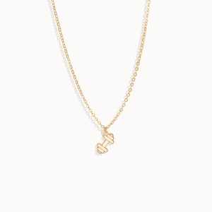 May include: A gold chain necklace with a small gold dumbbell pendant.