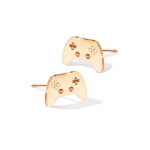 Puede incluir: Un par de pendientes de botón de color dorado con forma de mando de videojuego.