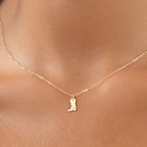 May include: A gold chain necklace with a small boot charm pendant.