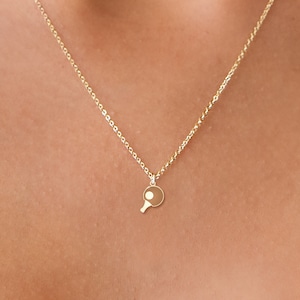 May include: A gold chain necklace with a small ping pong paddle pendant.