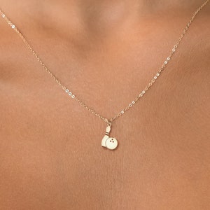 May include: A gold chain necklace with a small pendant featuring a bowling pin and ball.