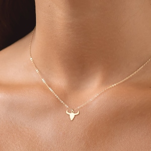 May include: A gold chain necklace with a small bull head pendant.