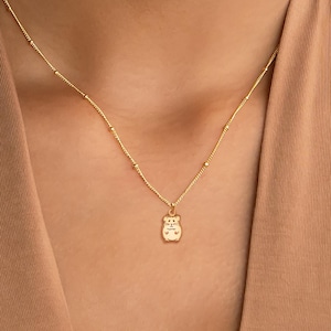 Könnte beinhalten: Eine goldene Kettenkette mit einem kleinen Hamster-Anhänger.