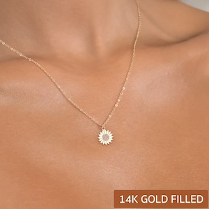 Könnte beinhalten: Eine zarte goldene Kettenkette mit einem kleinen Sonnenblumenanhänger. Die Kette ist 14 Karat Gold gefüllt.