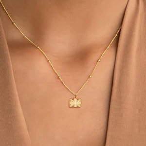 Puede incluir: Un collar de cadena dorada con un pequeño colgante con la bandera del Reino Unido.