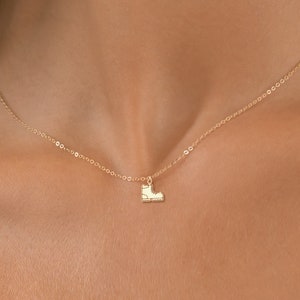 May include: A gold chain necklace with a small boot charm pendant.