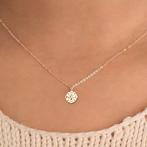 May include: A gold chain necklace with a small gold pendant featuring a stylised fire department symbol.