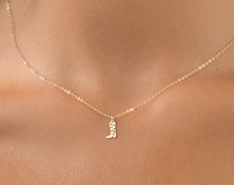 May include: A gold chain necklace with a small boot pendant.