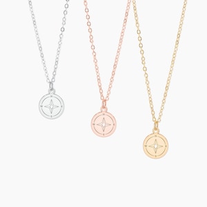 May include: Three delicate gold, silver, and rose gold necklaces with compass charms. Each charm features a compass rose with a four-pointed star in the center.