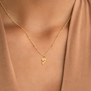 May include: A gold chain necklace with a small pizza slice pendant.