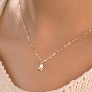 Könnte beinhalten: Eine zarte goldene Kettenkette mit einem kleinen, minimalistischen Schmetterlingsanhänger.
