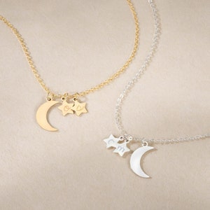 May include: Two gold and silver necklaces with crescent moon and star charms. The gold necklace has a charm with the initials "O & D" and the silver necklace has a charm with the initials "C & M".