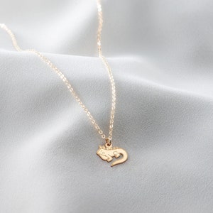 May include: A gold chain necklace with a small gold lizard pendant.