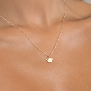 May include: A gold chain necklace with a small teapot pendant.