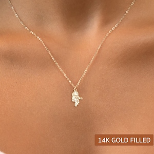 Puede incluir: Un collar de oro relleno con un pequeño dije de astronauta. 14K Gold Filled.