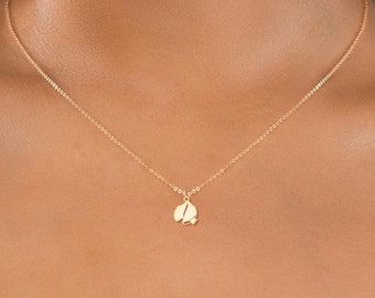 May include: A gold chain necklace with a small, delicate pendant shaped like a leaf.
