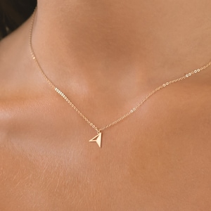 May include: A gold chain necklace with a small paper airplane pendant.