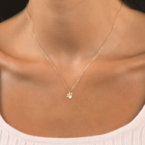May include: A delicate gold chain necklace with a small crown pendant.
