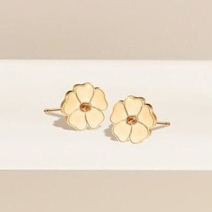Op de afbeelding: Een paar gouden oorbel studs in de vorm van een bloem met wit emaille.