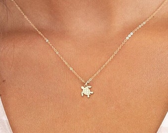 May include: A delicate gold chain necklace with a small turtle pendant.