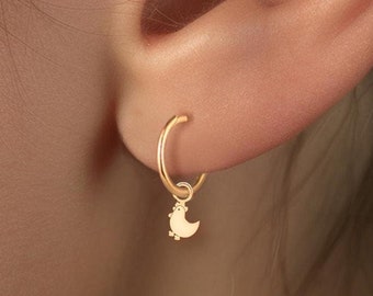 May include: Gold hoop earrings with a small crescent moon charm hanging from each hoop.