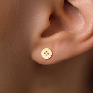 Może przedstawiać: Złote kolczyki-sztyfty w kształcie guzika z czterema małymi złotymi kropkami w środku.