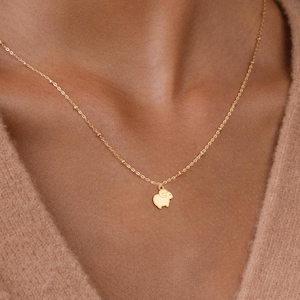 May include: A gold chain necklace with a small, gold, pig-shaped pendant.