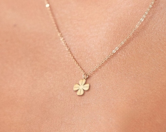 May include: A delicate gold necklace with a small four-leaf clover pendant.