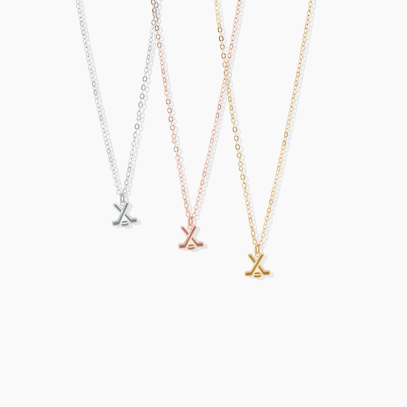 Pu&ograve; includere: Tre collane in argento, oro rosa e oro con un ciondolo a forma di bastone da hockey e disco.