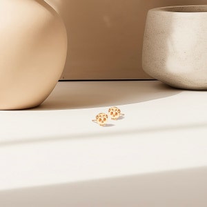 May include: A pair of gold-toned skull stud earrings. The skulls have a detailed design with small holes throughout.