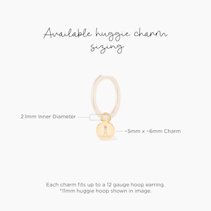 May include: Gold huggie hoop earring with a small lighthouse charm. The hoop is 2.1 mm in diameter and the charm is approximately 5 mm by 6 mm.  Each charm fits up to a 12 gauge hoop earring.  The image shows an 11 mm huggie hoop.