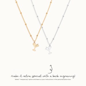May include: Two gold and silver necklaces with a martini glass charm. The silver necklace has a letter "B" engraved on the back of the charm. The text "make it extra special with a back engraving!" is written below the necklaces.