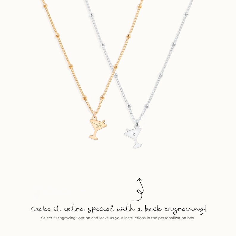 May include: Two gold and silver necklaces with a martini glass charm. The silver necklace has a letter "B" engraved on the back of the charm. The text "make it extra special with a back engraving!" is written below the necklaces.