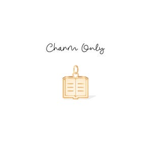 Op de afbeelding: Een goudkleurige bedel in de vorm van een open boek. De bedel heeft een kleine lus aan de bovenkant om aan een ketting of armband te bevestigen. De tekst "Charm Only" staat boven de bedel.