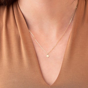 Pu&ograve; includere: Una collana con catena dorata con un piccolo ciondolo rotondo con un design a pallavolo.