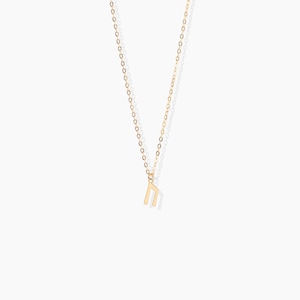 K&ouml;nnte beinhalten: Eine goldene Kettenkette mit einem kleinen goldenen Anh&auml;nger in Form des Buchstabens "n".