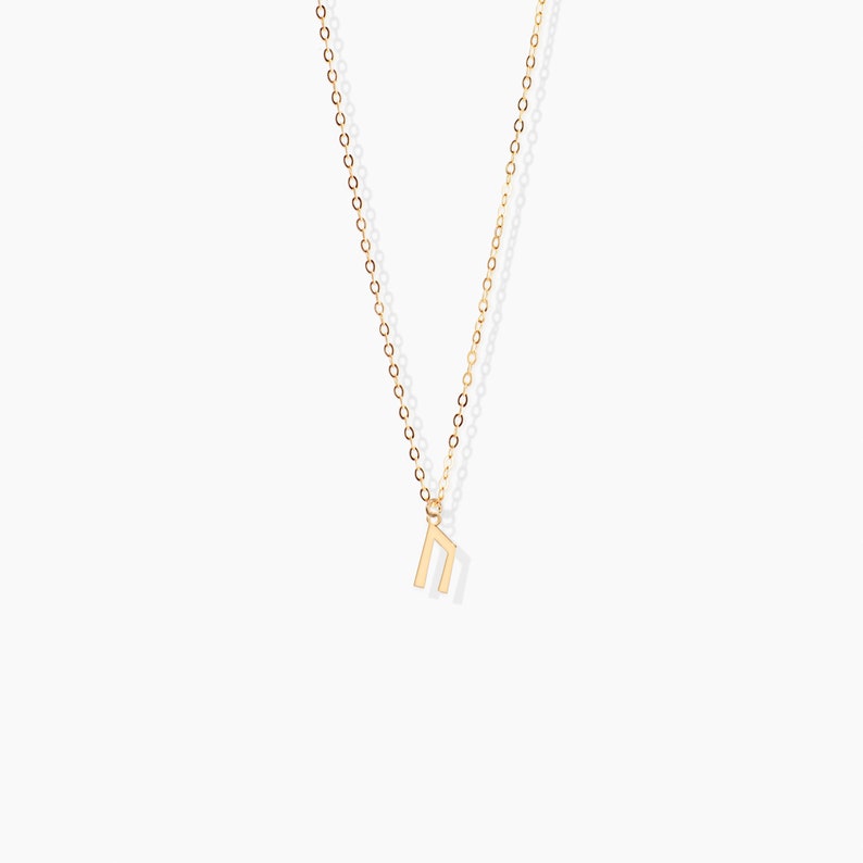 K&ouml;nnte beinhalten: Eine goldene Kettenkette mit einem kleinen goldenen Anh&auml;nger in Form des Buchstabens "n".