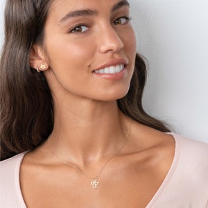 May include: A gold necklace with a delicate angel pendant. The necklace is worn by a person with long brown hair.