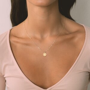Delicate gold charm pendant necklace featuring a minimalist round charm. Ideal for everyday wear or special occasions, this timeless piece appeals to modern fashion lovers seeking elegance.