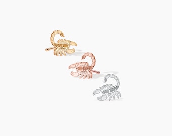 May include: Three pairs of scorpion stud earrings in gold, rose gold, and silver.
