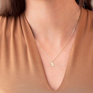 May include: A gold chain necklace with a small shoe charm pendant.