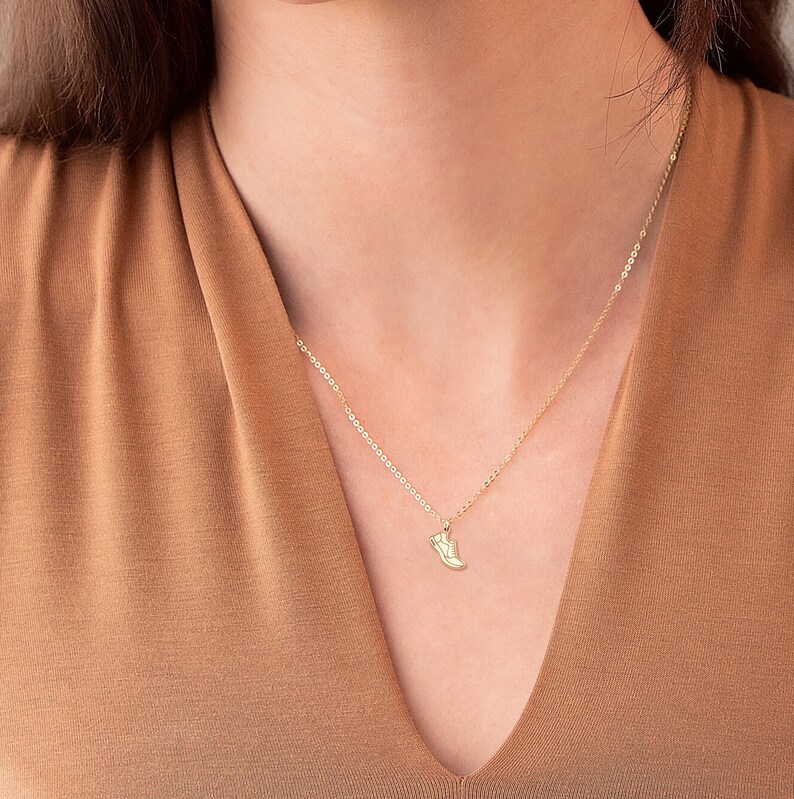 May include: A gold chain necklace with a small shoe charm pendant.