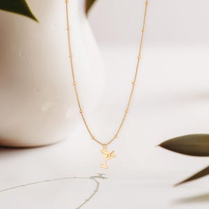 May include: A gold chain necklace with a small gold charm of a martini glass.
