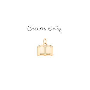May include: A gold-colored charm in the shape of an open book. The charm has a loop at the top for attaching to a necklace or bracelet. The text "Charm Only" is written above the charm.