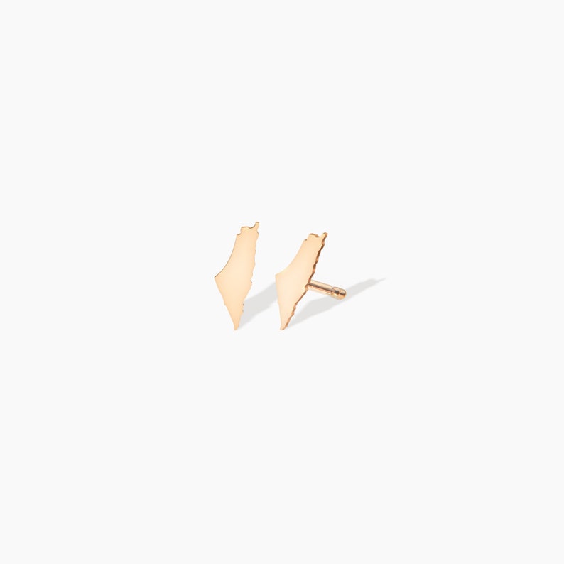 May include: A pair of gold earrings shaped like the outline of Israel.