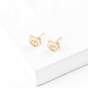May include: A pair of gold bear-shaped stud earrings. The earrings are small and delicate, and they would make a great gift for a child.