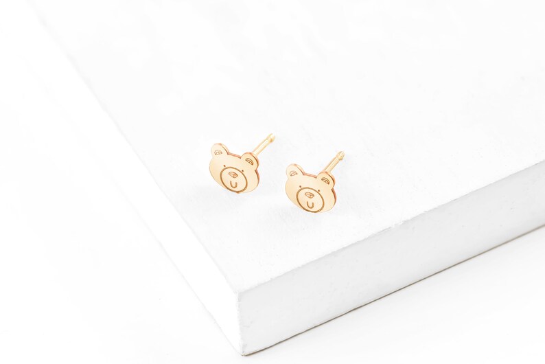 May include: A pair of gold bear-shaped stud earrings. The earrings are small and delicate, and they would make a great gift for a child.