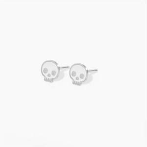 Puede incluir: Un par de pendientes de bot&oacute;n de calavera de plata. Las calaveras son blancas con ojos negros.